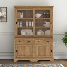 a wooden hutch with glass doors and dishes on it's shelves in a living room