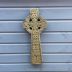 an ornate gold cross hanging on the side of a building in front of a blue wall