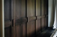 a room with wooden paneling and white curtains