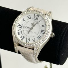 This Juicy Couture Is A Stainless Steel Quartz Watch. Features A Crystallized Bezel And A White Face With Roman Numeral Numbers. The Face, Also, Has The Juicy Couture Name And Logo. The Hands Of The Watch Have The Logo On The Ends. The Leather Band Features A Metallic Sheen To It. Watch Is In New Condition With Tags And Original Box. There Are Some Imperfections On The Case, Where There Is Some Discoloration On The 4 Ends That Attach To The Strap, As Well As, Some Areas Around The Face. Please S Roman Numeral Numbers, Numeral Numbers, Juicy Couture Watch, Juicy Couture Accessories, White Watch, Couture Accessories, Crystal Watches, White Face, Roman Numeral