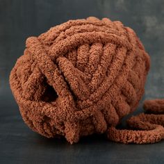 a ball of brown yarn sitting on top of a black table next to a pair of scissors