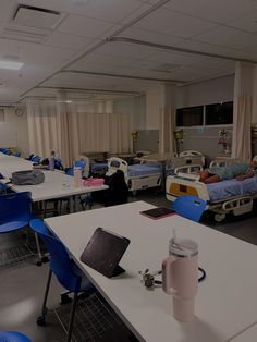 a hospital room filled with beds and desks next to each other on top of white tables