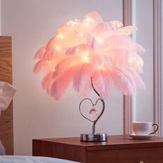 a lamp that is on top of a table next to a bed with a cup and saucer