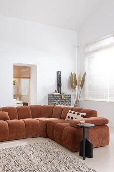 a living room with a large sectional couch and rug on the floor in front of a window