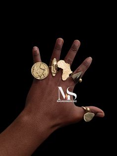 a person's hand with three different rings on it and two gold coins in the middle