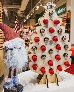 a wooden christmas tree with red and white ornaments on display in a store or showroom