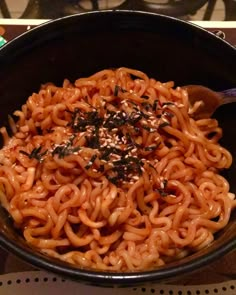 a black bowl filled with noodles on top of a stove