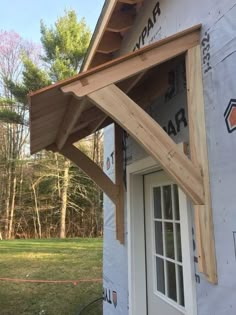 a house being built with wood framing and siding on the front door, window frames in place