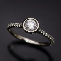 a white gold ring with diamonds on the sides and a round diamond in the center