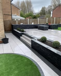 an outdoor patio with steps and landscaping in the middle, surrounded by green lawning