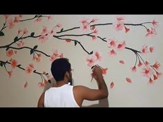 a man painting a wall with flowers on it