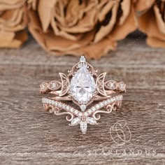 an engagement ring set with a pear shaped diamond surrounded by smaller round diamonds on a wooden surface