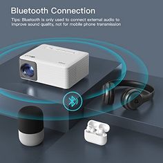 an image of a bluetooth projector with headphones and earbuds on the table