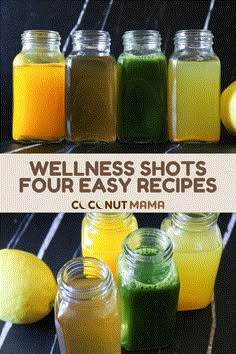 four jars filled with different colored liquids next to lemons and limes on a table