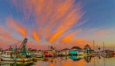 colorful clouds are reflected in the water near boats and houses at sunset or sunrise time