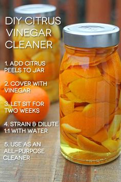 a jar filled with orange peels sitting on top of a wooden table next to other fruit