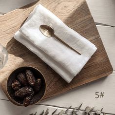 a wooden tray topped with a bowl of raisins next to a white napkin