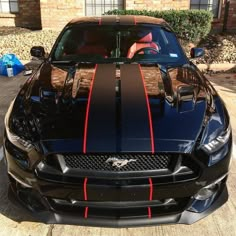 a black mustang with red stripes parked in front of a house