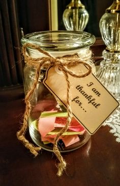 a glass jar filled with lots of different colored pieces of paper on top of a wooden table