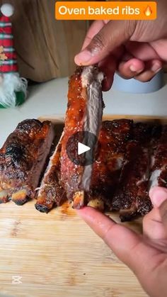 someone is cutting up some ribs on a wooden board with the words oven baked ribs