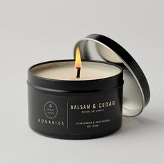 a candle that is inside of a tin on a white surface with the lid open