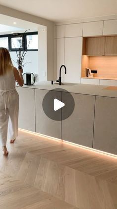 a woman is walking through the kitchen in her pajamas and white robe, while looking into the dining room