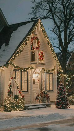 a white house covered in christmas lights and wreaths