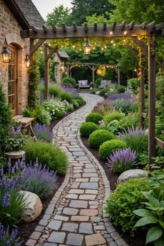 a stone path leads to a garden with lavender flowers and lights hanging from the pergolated arbor