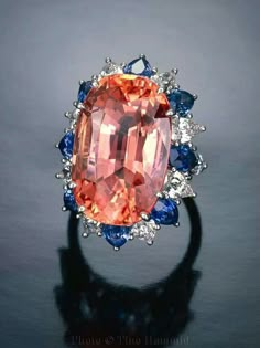 30-karat Padparadscha sapphire surrounded by blue sapphires and diamonds. Padparadscha Sapphire, Fabulous Jewelry, Precious Gems, Gems And Minerals, Gems Jewelry, High Jewelry, All That Glitters, Sri Lanka