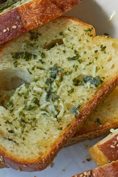 slices of bread with pesto on them sitting on top of a white plate next to another piece of bread