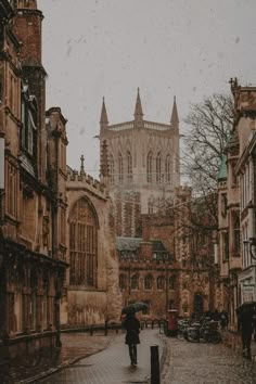 a person walking down a street with an umbrella in front of a church on a rainy day