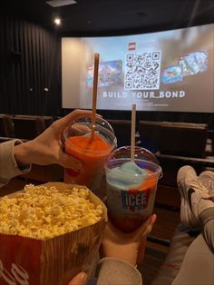 two people holding up drinks and popcorn in front of a projector screen with the words build your bond on it