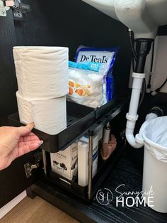 Woman pulls out sliding tray under the bathroom sink holding toilet paper, cotton balls and epsom salt.