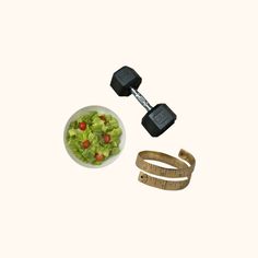 a bowl of salad next to a pair of dumbbells