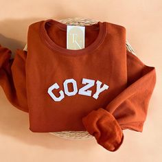 Cozy up with our Cozy Crewneck Sweatshirt this fall season! - Sweatshirt is super soft and comfy! ♡ - Sweatshirt composition: 50% cotton, 50% polyester - All our sweatshirts run a unisex fit. They are naturally oversized, so we normally recommend your true size. But if you like a more baggy look, we recommend sizing up. - These letters are iron-on patched and is heat pressed, not embroidered. But rest assured they've been tested and won't fall off! - Please note that crewneck brand used may vary Cozy College Sweater With Ribbed Cuffs, Cozy Brown Sweatshirt For Loungewear, Cozy Letter Print Tops For Fall, Cozy Fleece Tops For Everyday, Cozy Everyday Fleece Top, Cozy Fit Cotton Sweatshirt, Cozy Cotton Sweater, Cozy Brown Cotton Top, Comfy Crew Neck Winter Tops