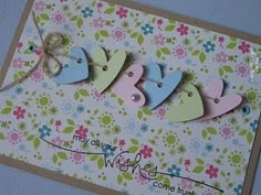 a card with four hearts on it and a ribbon attached to the front, in pastel colors