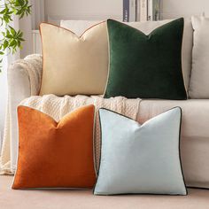 three different colored pillows sitting on top of a couch