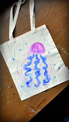 a white bag with a pink and blue jellyfish on it sitting on a wooden table