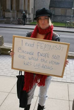 a woman holding a sign that says i need feminist because people still hate what the victim wears