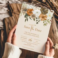 a person holding up a wedding card with flowers on the front and bottom, which reads save the date