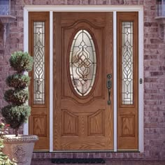 a wooden door with glass and potted plant in front of it on a brick building