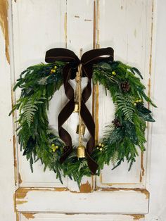 a wreath on the front door is decorated with green leaves and pine cones