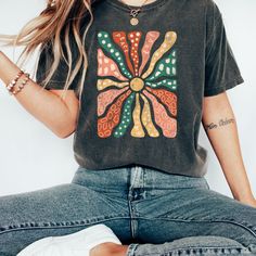 "Retro Groovy Flowers Shirt Vintage Shirt Boho Daisy Flower Tee Shirt Botanical Tee Boho Tee Wildflower Shirt Plant Shirt Botanical Shirt  Comfort Colors introduces the \"Comfort Colors 1717\" garment-dyed t-shirt; a fully customizable tee made 100% with ring-spun cotton. The soft-washed, garment-dyed fabric brings extra coziness to your wardrobe while the relaxed fit makes it an excellent daily choice. The double-needle stitching throughout the tee makes it highly durable while the lack of side-seams helps the shirt retain its tubular shape.  The Comfort Colors 1717 tee is made with medium fabric (6.1 oz/yd² (206.8 g/m consisting of high quality, 100% ring-spun US cotton for long-lasting comfort. The relaxed fit keeps the wearer comfy in both casual and semi-formal settings while the crew Patterned Floral Print Cotton T-shirt, Spring Casual T-shirt With Abstract Print, Casual Spring T-shirt With Abstract Print, Floral Print Cotton T-shirt, Multicolor Abstract Print T-shirt For Spring, Casual Multicolor Tops With Unique Print, Green Bohemian Top With Graphic Print, Casual Multicolor Floral Print Top, Green Abstract Print Relaxed Fit Top