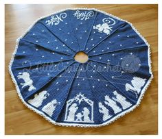 a blue and white crocheted christmas tree skirt on top of a wooden floor