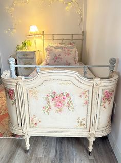 a white bed with pink flowers on the headboard and foot board in a bedroom