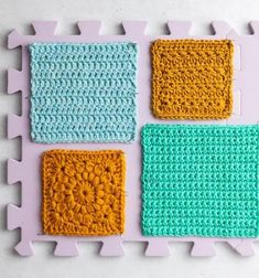 four crocheted squares are arranged on a white surface