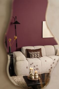 a living room with a couch, table and mirror reflecting it's reflection in the wall