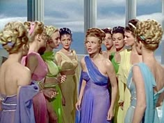 several women in evening dresses talking to each other while one looks at the woman's face