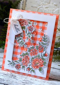 an orange and white card that has flowers on it, with a tag hanging from the front