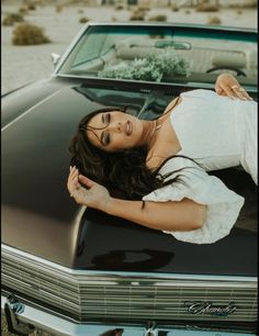 a woman laying on the hood of a car